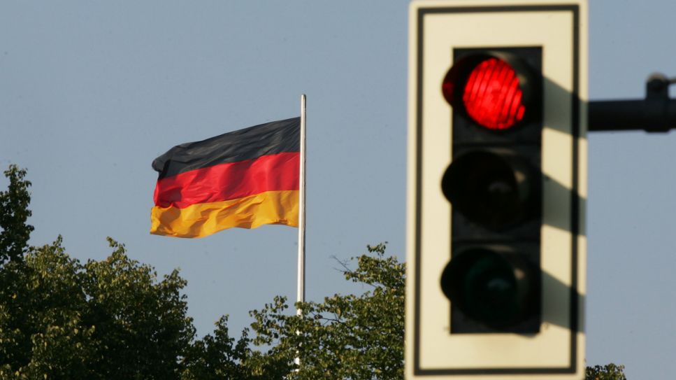 Auf Rot steht die Ampel neben der schwarz-rot-goldenen Fahne der Bundesrepublik Deutschland © picture-alliance/ ZB/ Soeren Stache 