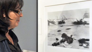 D-Day: Eine Journalistin betrachtet ein Foto von Robert Capa, das US-Soldaten bei der Landung am Omaha Beach zeigt; © picture-alliance/MTI/Lajos Soos
