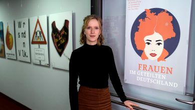 Kuratorin Claudia Marz in ihrem Büro vor dem Plakat der Ausstellung Frauen im geteilten Deutschland © picture alliance / AP/ Ebrahim Noroozi