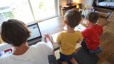 Corona-Krise – Die Mutter des sechsjährigen Jakob und des vierjährigen Valentin arbeitet Zuhause an einem Laptop, während ihre Kinder neben ihr malen und ein Buch ansehen. © picture alliance/dpa | Karl-Josef Hildenbrand